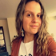 la imagen puede contener a una mujer de cabbelo castaño claro rizado,posando ligeramente sonreida.